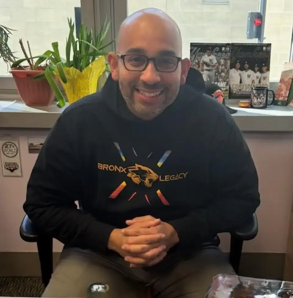 Staff member smiling in office wearing Bronx Legacy hoodie