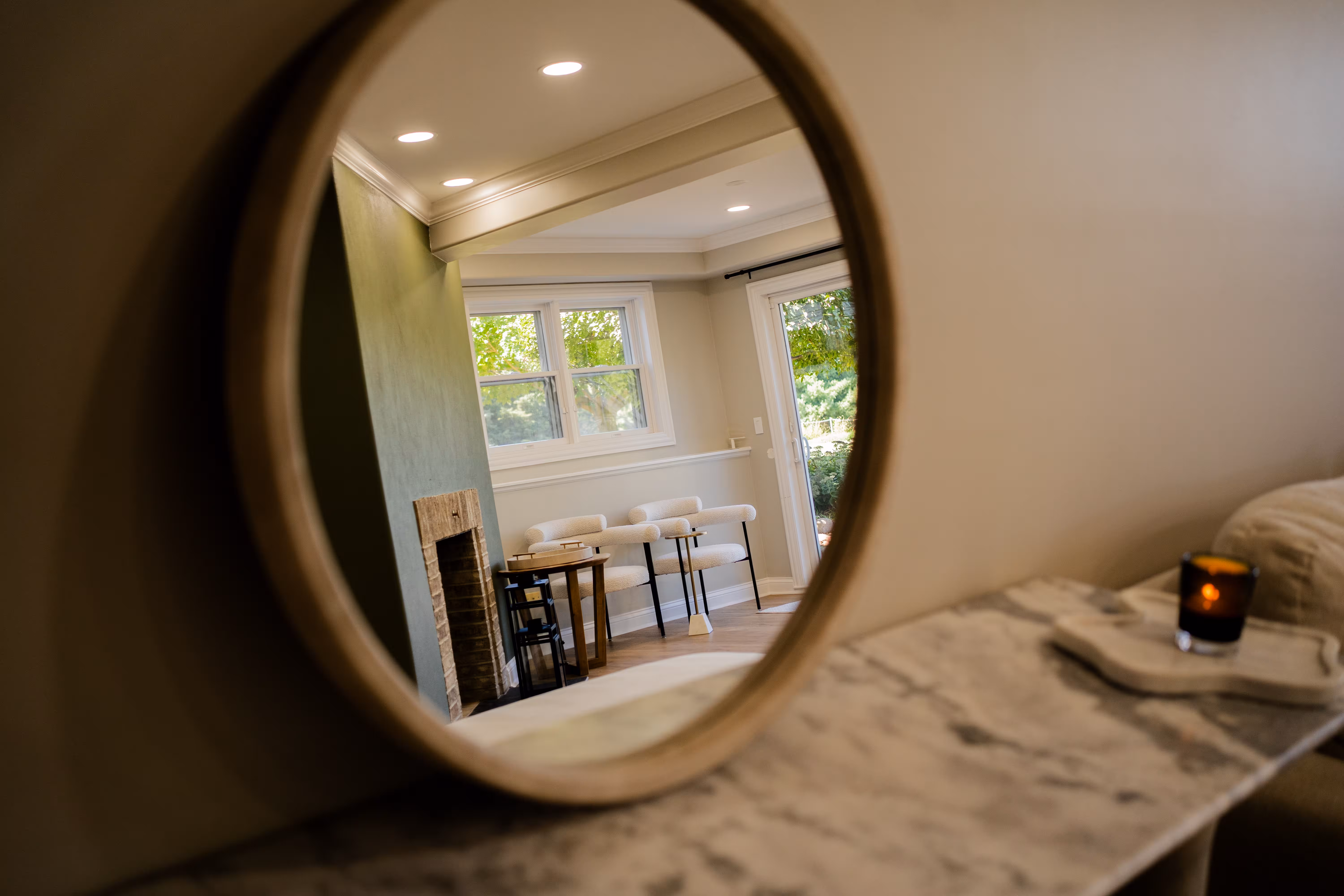 Round mirror above a marble console reflecting a freshly painted dining room
