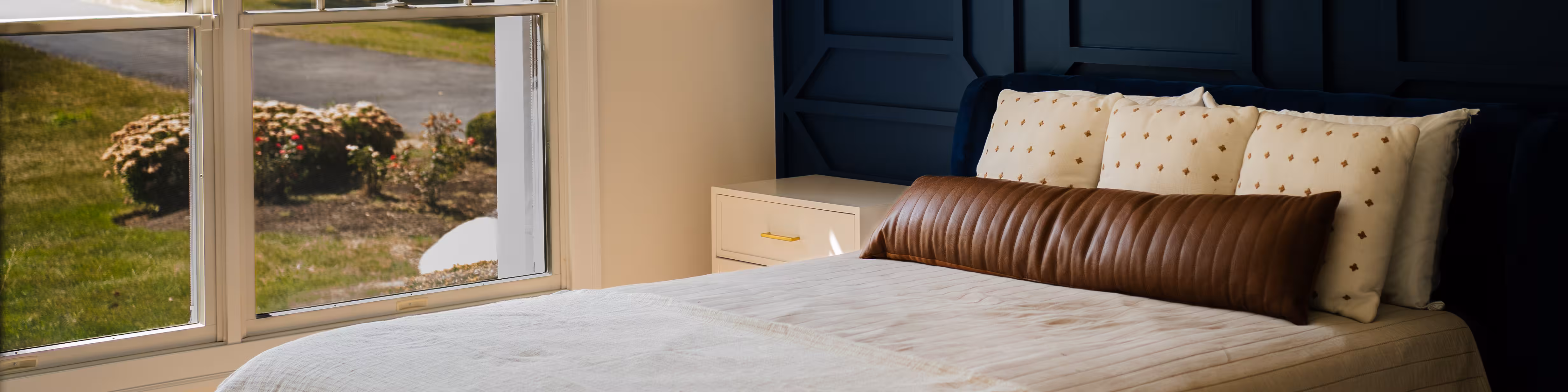 Navy paneled accent wall behind an upholstered bed in a repainted primary bedroom