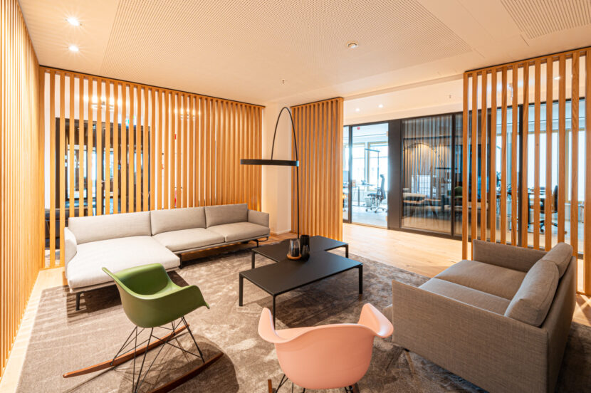 Loungebereich mit Sofas, Designerstühlen und Holzlamellen bei Delta Equity in München