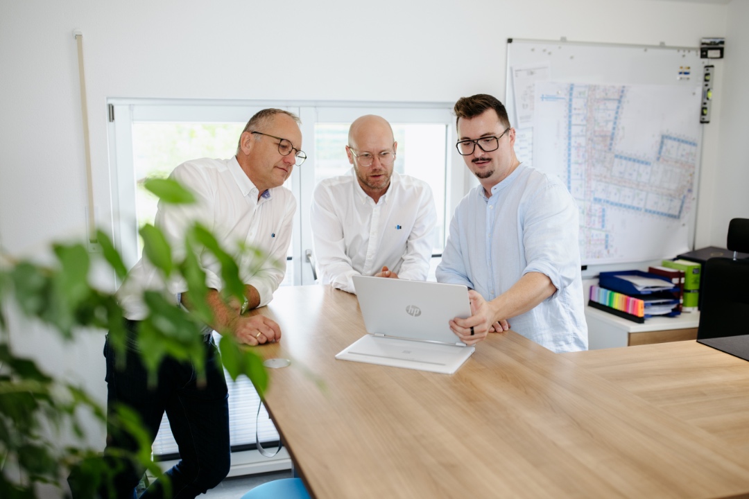Drei Mitarbeiter besprechen ein Projekt am Laptop im Besprechungsraum