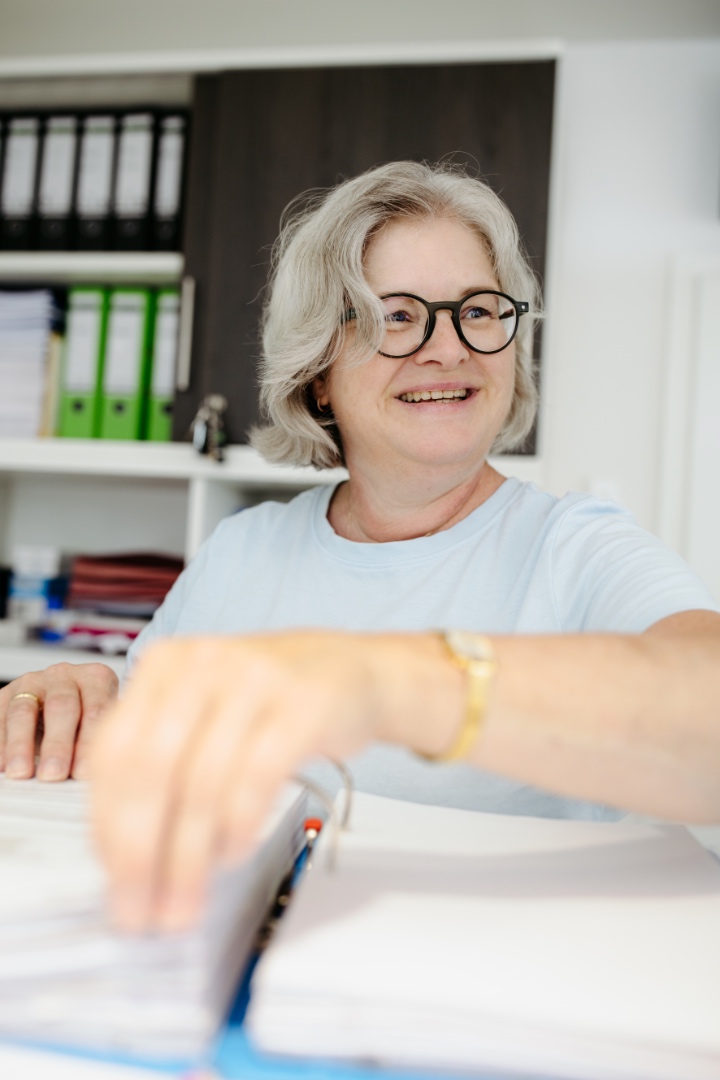 Mitarbeiterin mit Brille blättert in Unterlagen