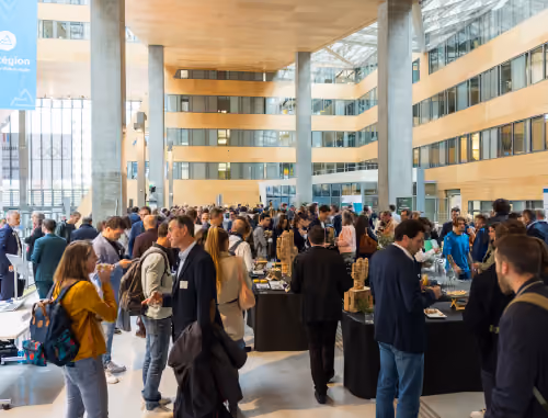 Large crowd mingling and eating in a modern, spacious conference or networking event hall.