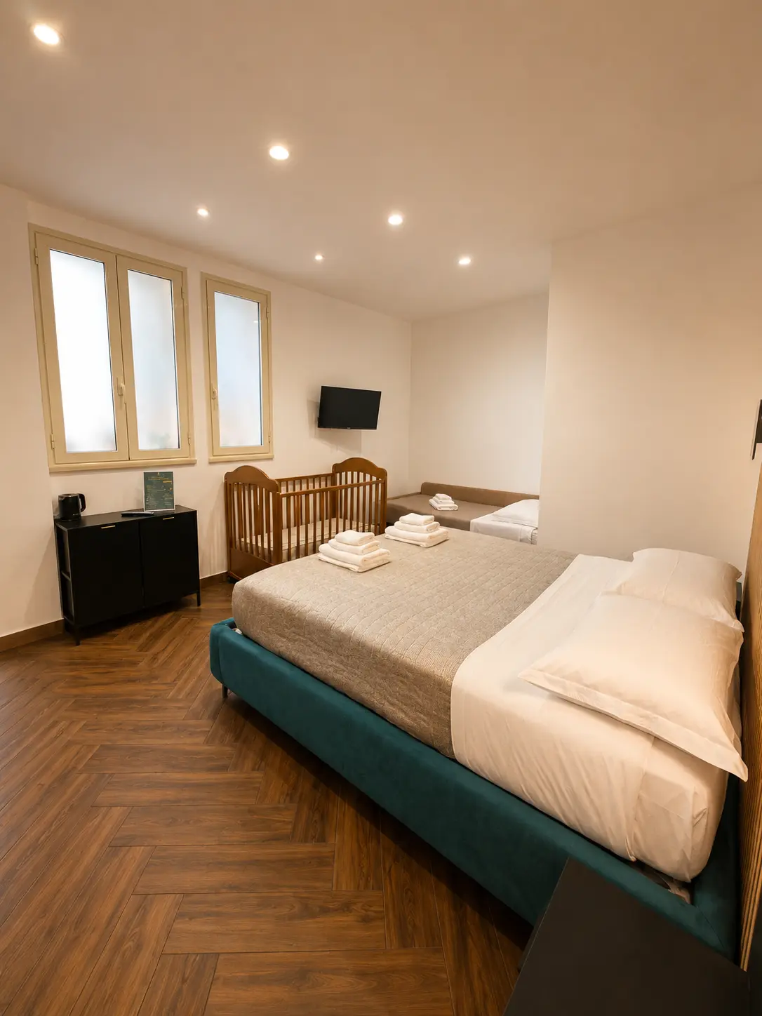 Camera elegante e accogliente con letto matrimoniale, letto singolo e culla, ideale per coppie e famiglie che cercano comfort e relax.