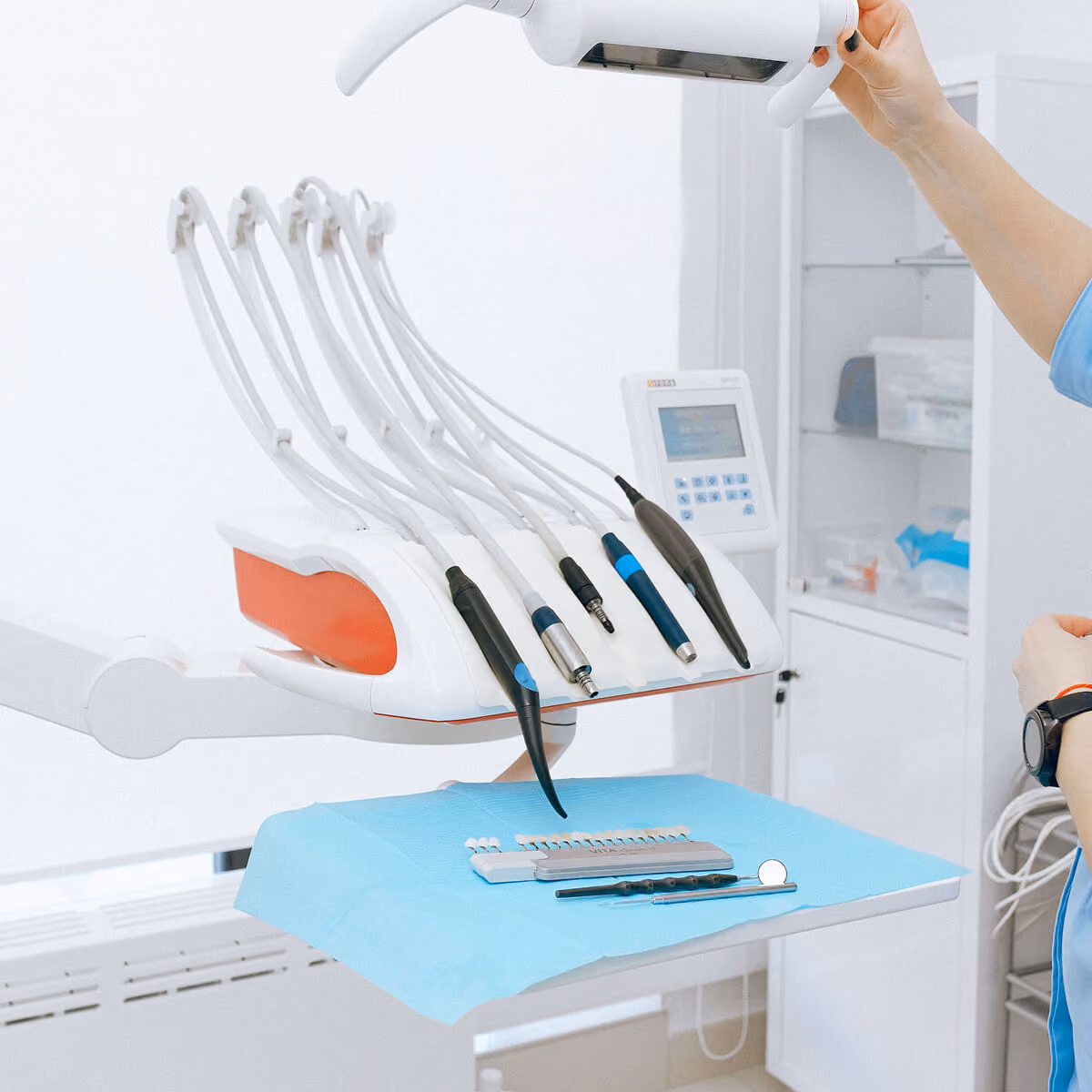 Dental instruments and tools on blue tray in a clean dental clinic setting.