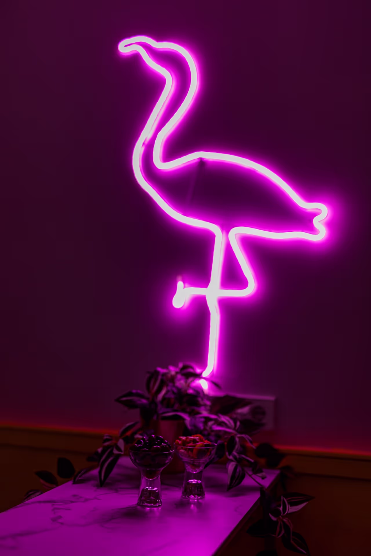 Roze neon flamingo tegen een paarse muur in een hippe cocktailbar in Amsterdam.