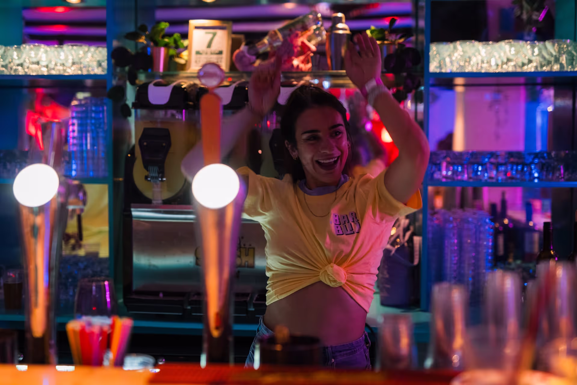 Vrouw in een gele blouse danst voor de bar tijdens een muziekavond in Amsterdam.
