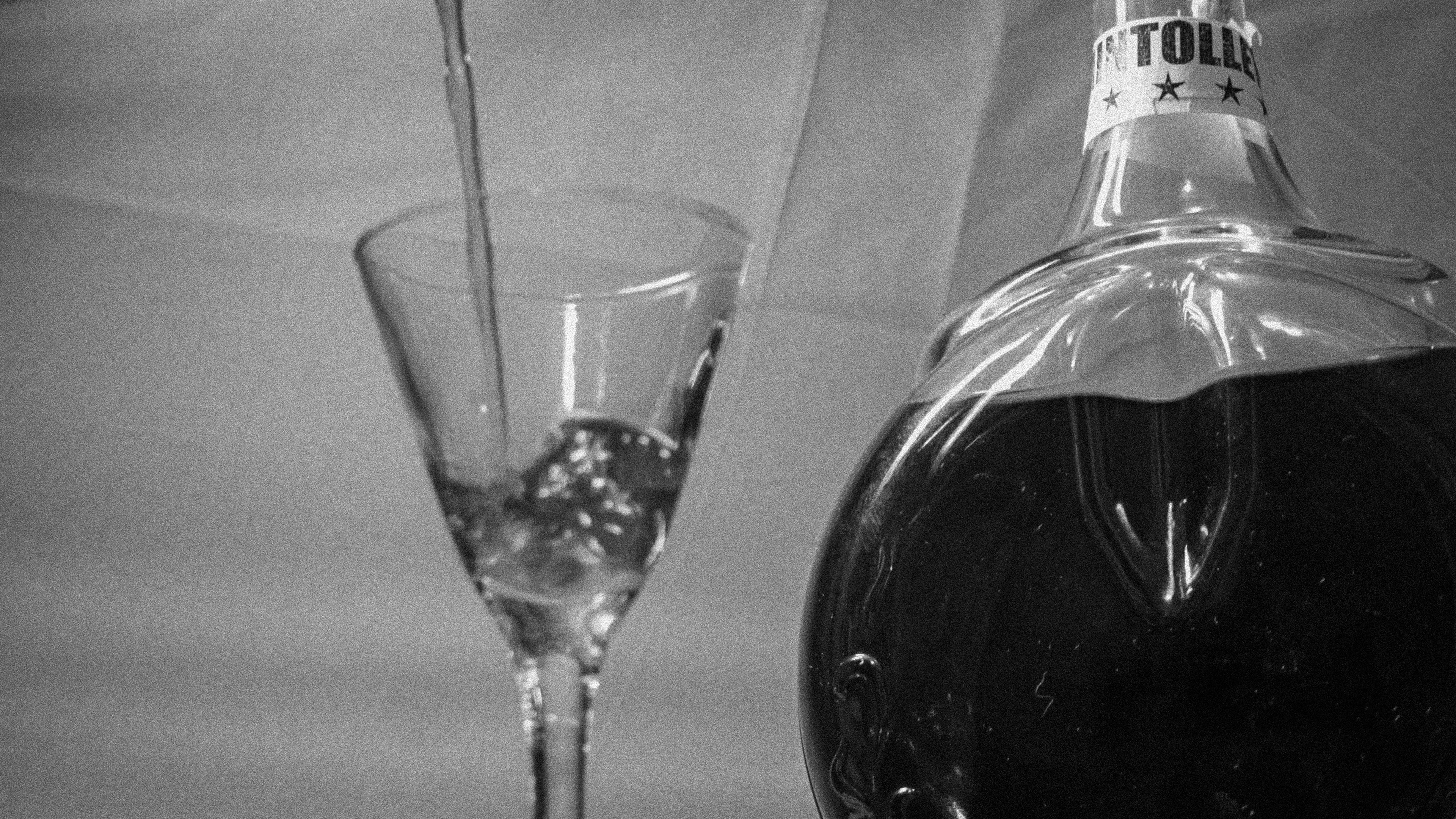 Mintolled bottle, a fine drink, next to a glass that is filled with this fine drink.