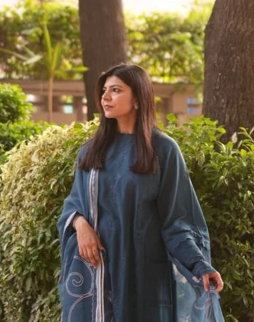 Anam Khalid, founder of Nuviel, seated in a garden in warm evening light.