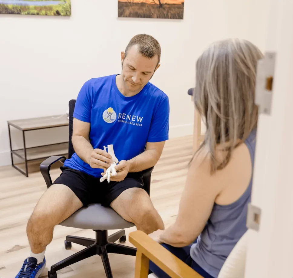 Matt Rieder, DPT, explaining a foot model to a patient at Renew Strength & Wellness in St. Augustine, FL