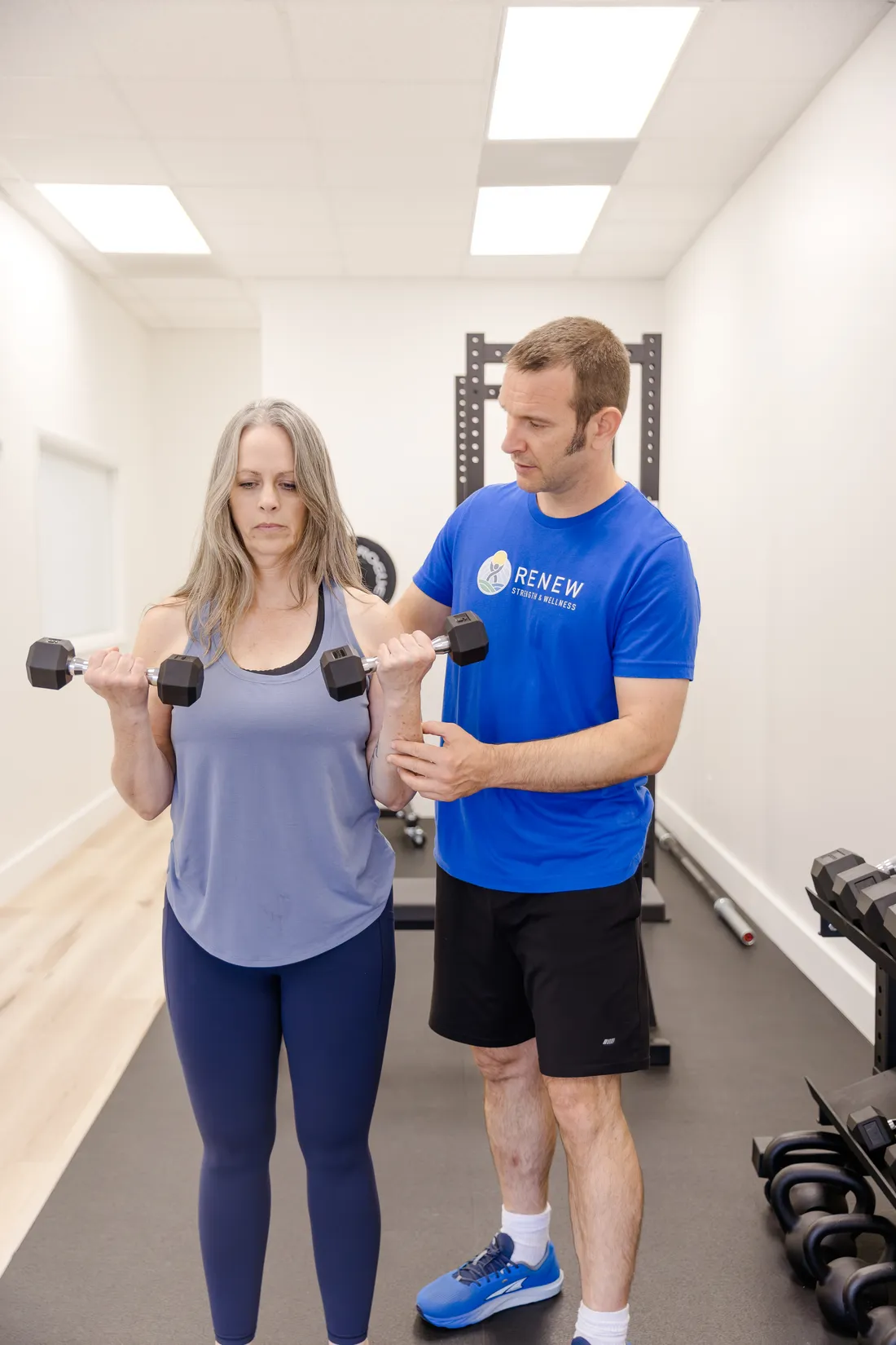 Matt Rieder, DPT, coaching a patient's dumbbell exercise during strength training at Renew Strength & Wellness in St. Augustine, FL