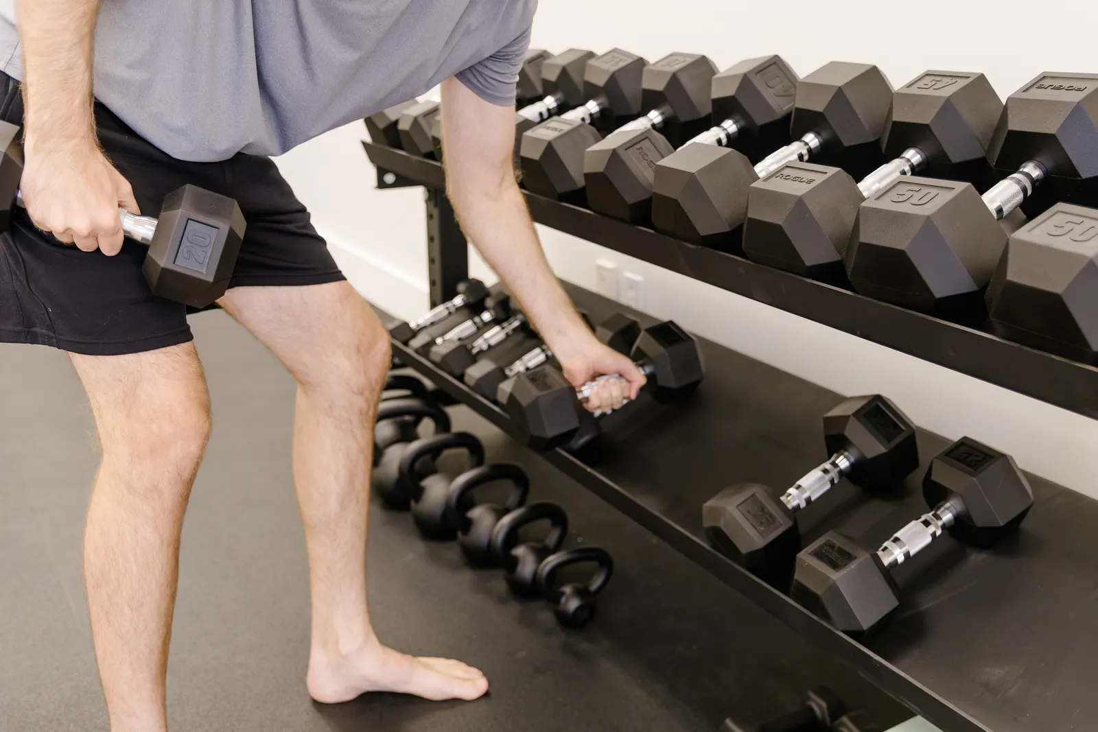 Renew client picking up a dumbbell from the rack during strength training