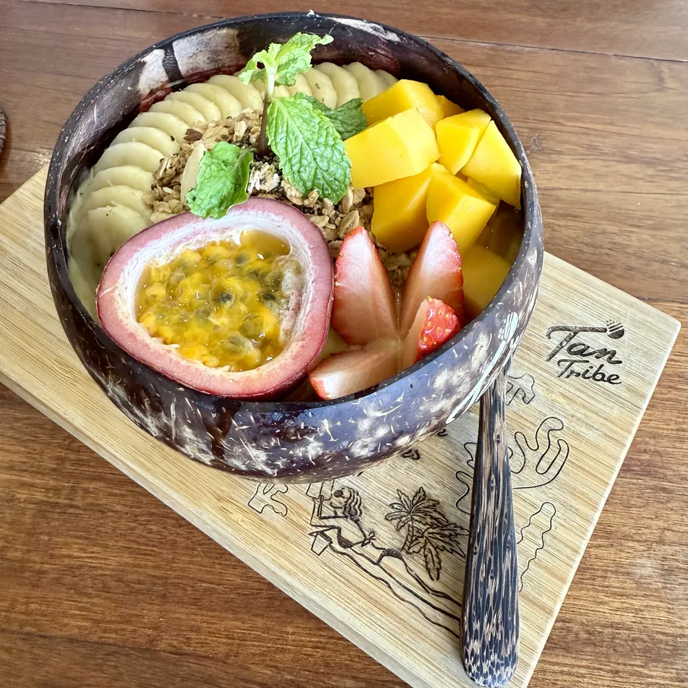 Smoothiebowl servert i kokosnøttskål med mango, jordbær, banan og pasjonsfrukt