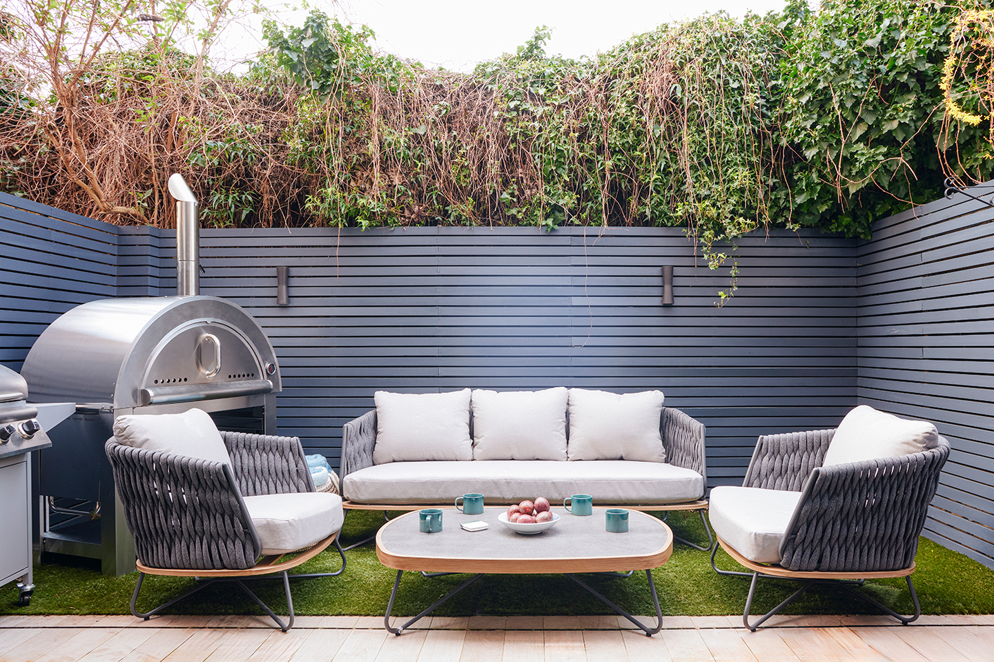 A fully fenced private garden with outdoor furniture, a dining area and a BBQ grill.