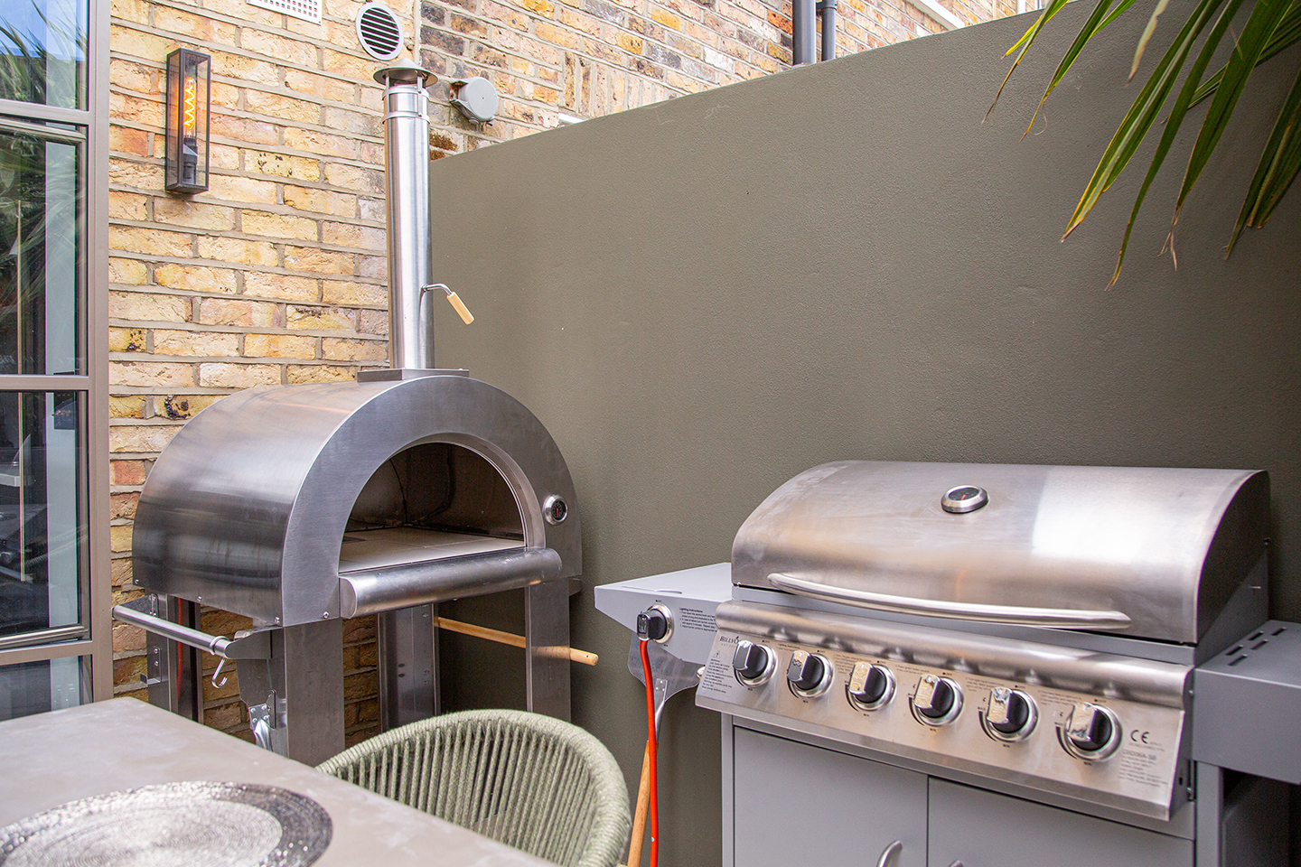 A stainless steel double oven, gas stove and dishwasher, with a dining table for shared meals.