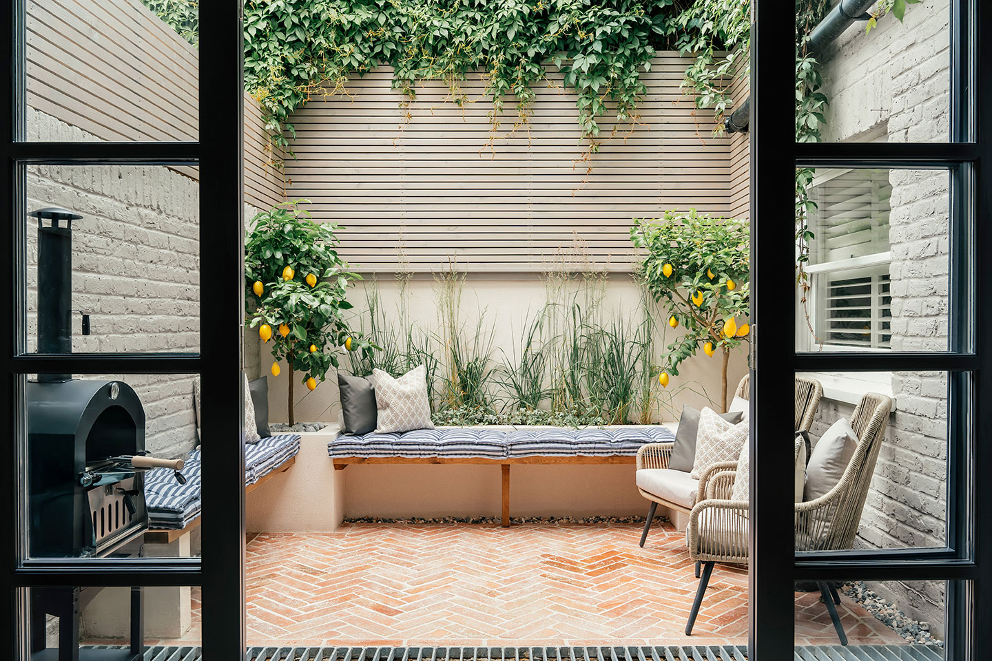 A fully fenced private garden with outdoor furniture, a dining area and a BBQ grill.