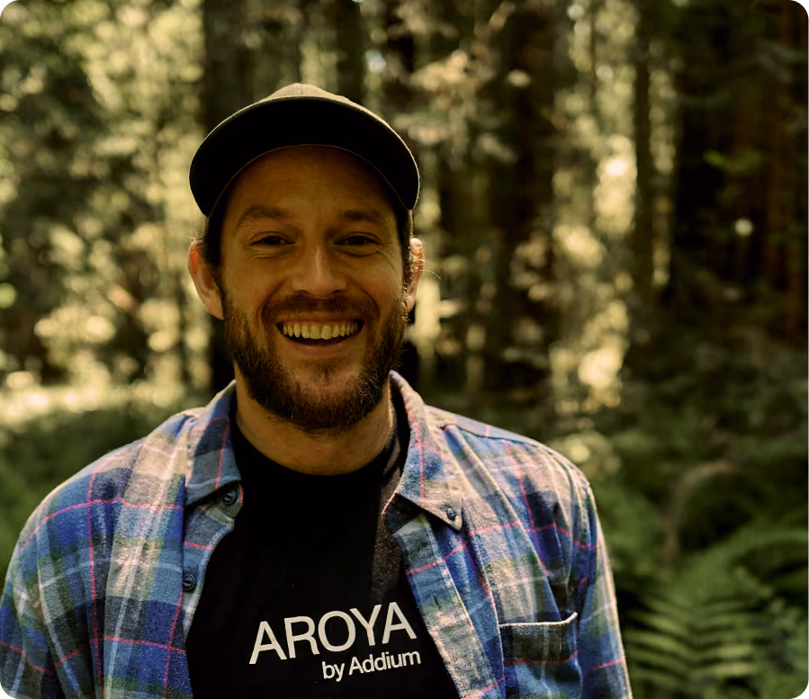 AROYA team member in an AROYA by Addium shirt standing in a forest
