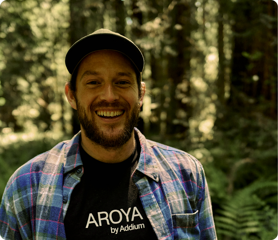 AROYA team member in an AROYA by Addium shirt standing in a forest