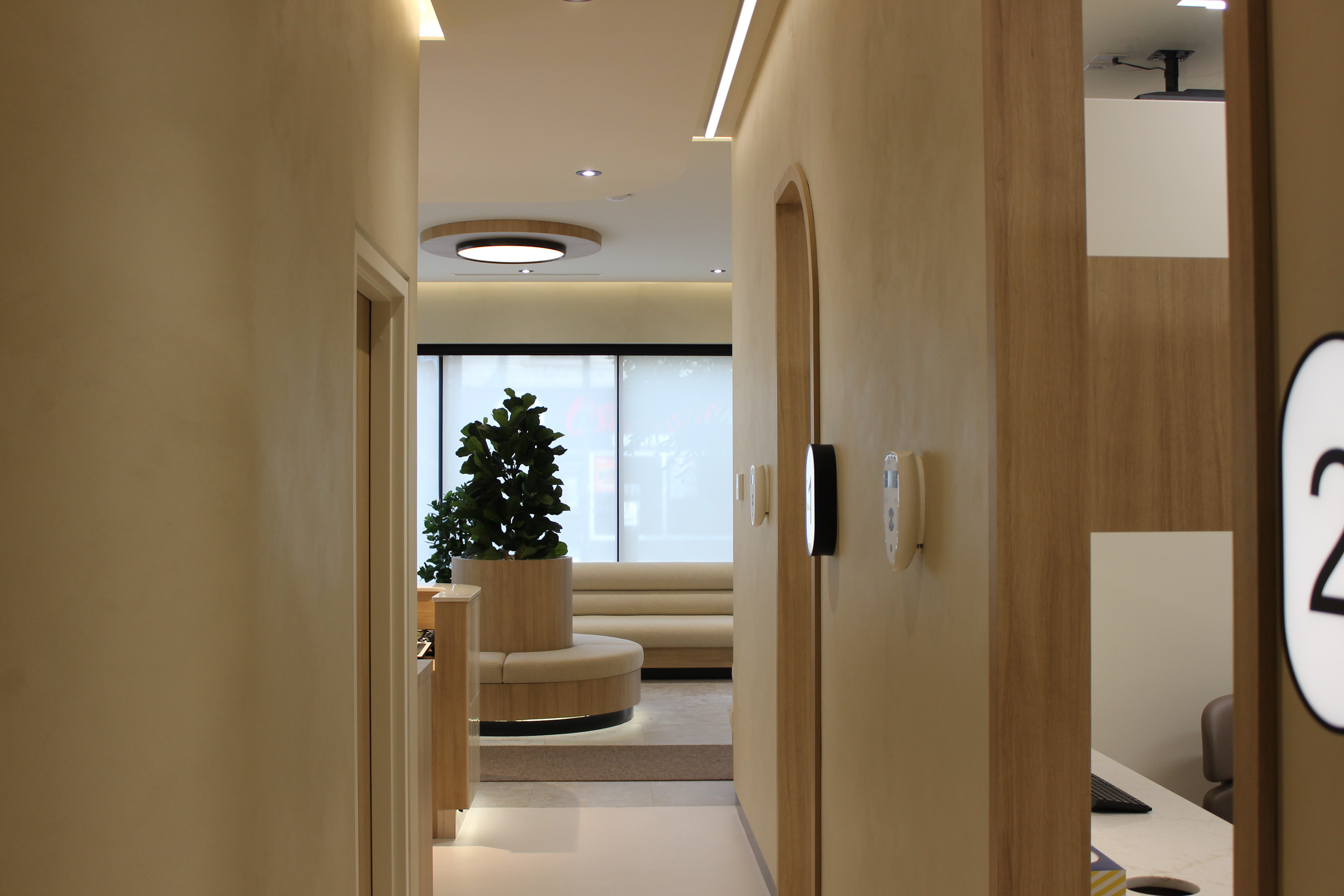 Intérieur d'une réception moderne avec comptoir, murs beige, signalétique et plantes vertes.