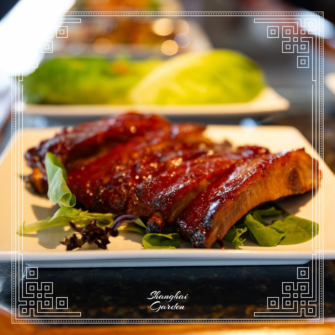 Barbecue ribs with glaze served on greens on a white square plate at Shanghai Garden.