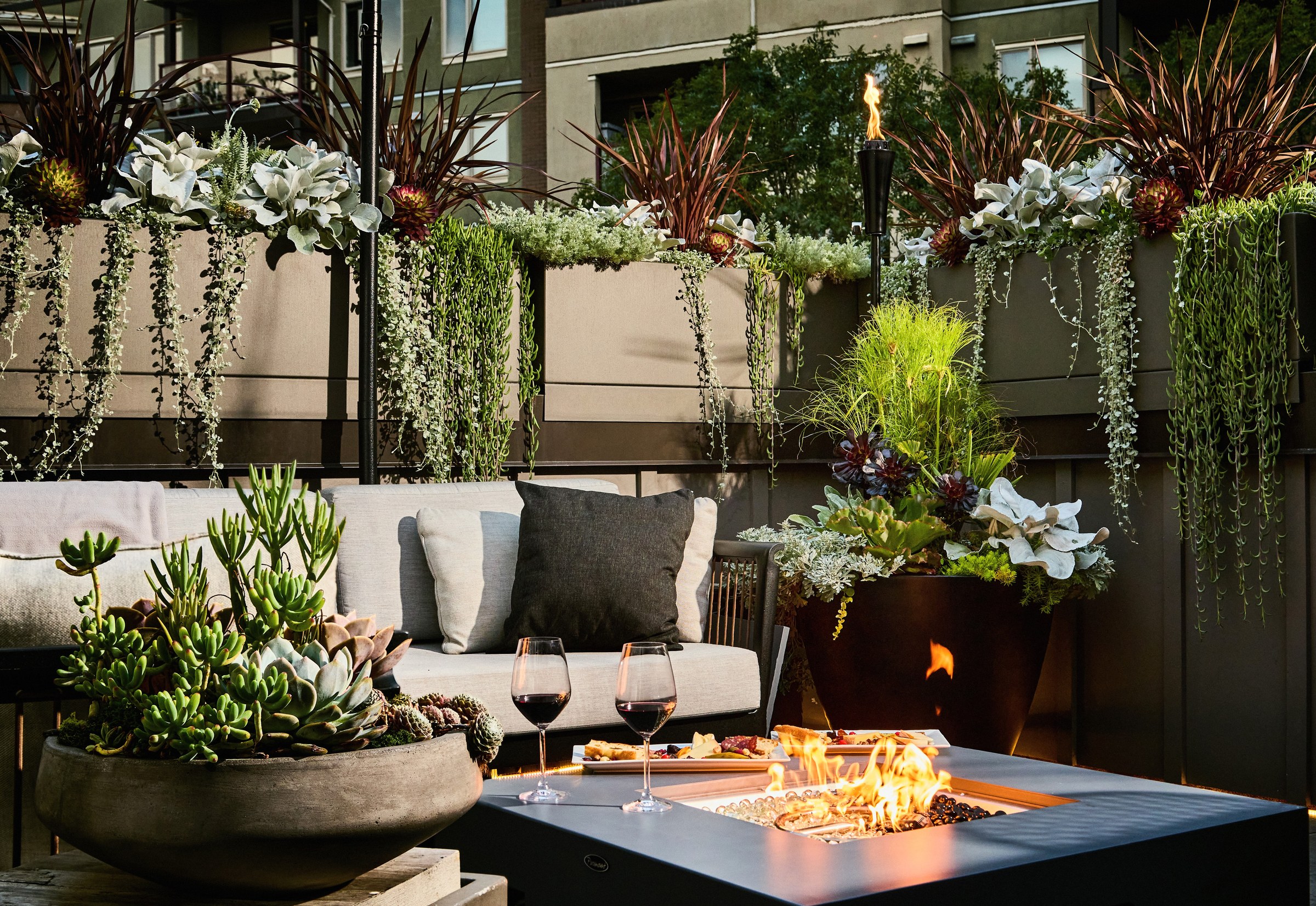 Rooftop lounge with a fire table burning at dusk, surrounded by succulent planters, Victoria Residence, ModPots design