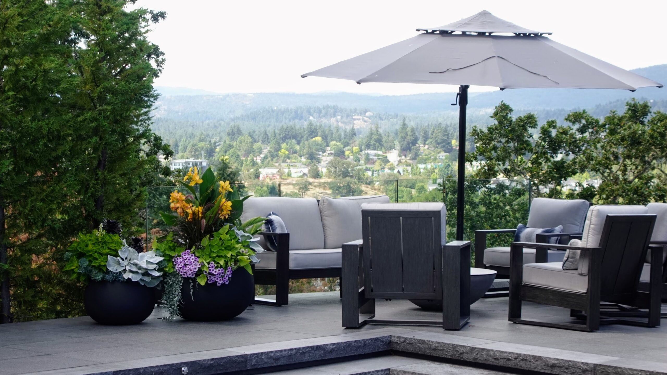 Black round planters with layered succulents, grasses, and flowering plants on a renovated patio, Broadmead Residence, ModPots design