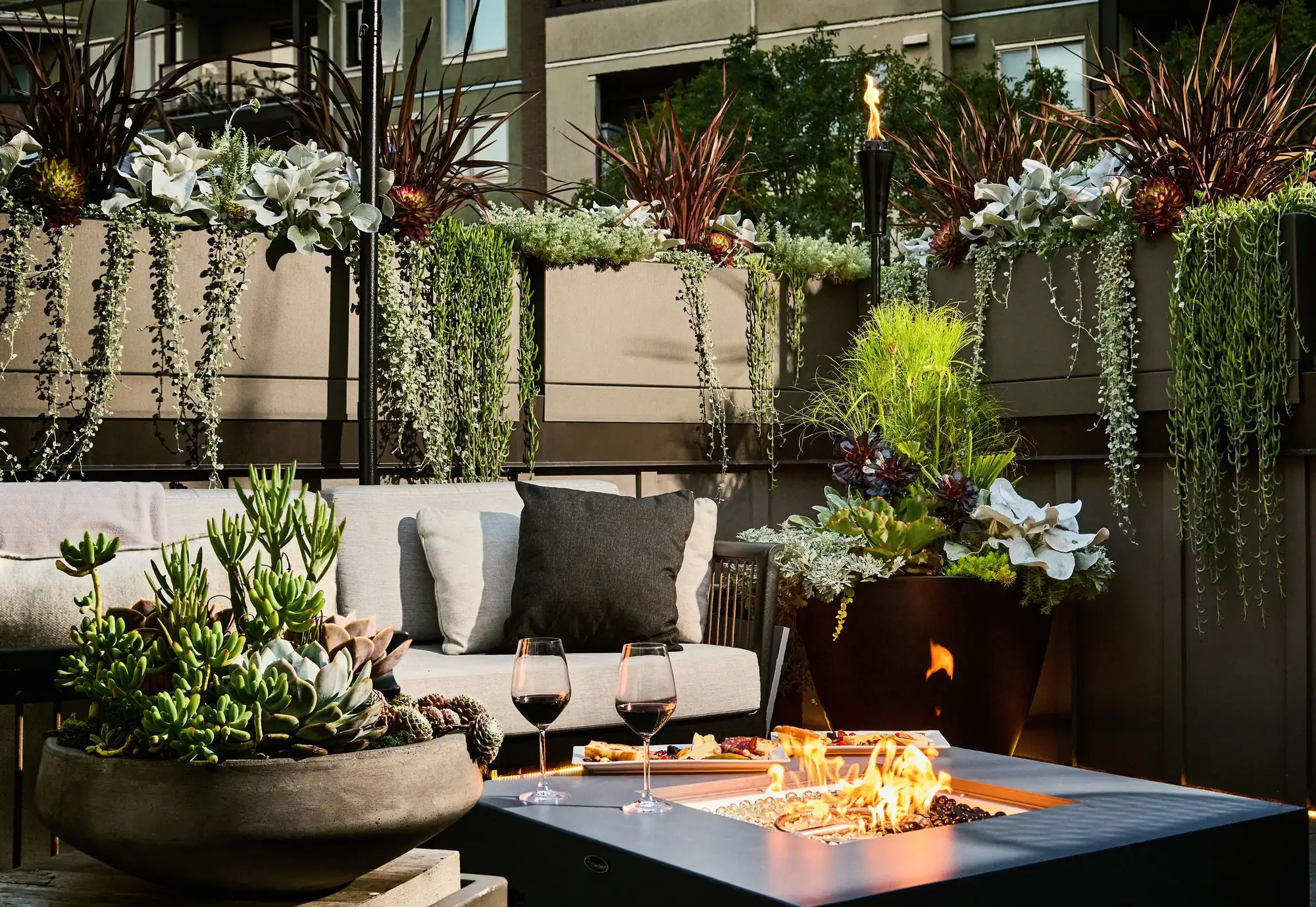 Rooftop lounge with a fire table burning at dusk, surrounded by succulent planters, Victoria Residence, ModPots design