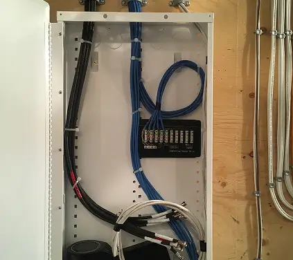 A white cabinet filled with various wires and cables, organized for easy access and management.