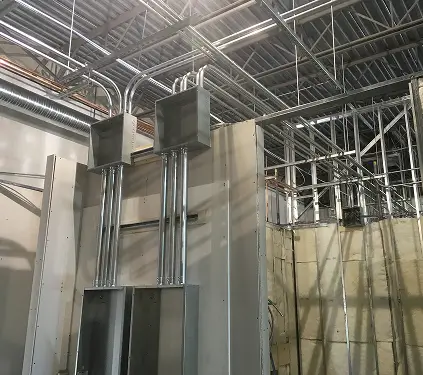 A room featuring exposed metal pipes and electrical wires, showcasing an industrial design aesthetic.