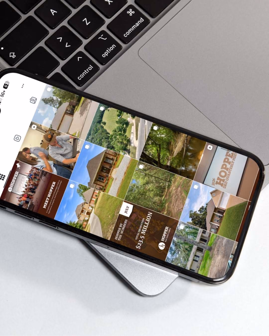 Smartphone displaying Hopper Real Estate Leaders social media grid of central Mississippi real estate photos and promotional posts.