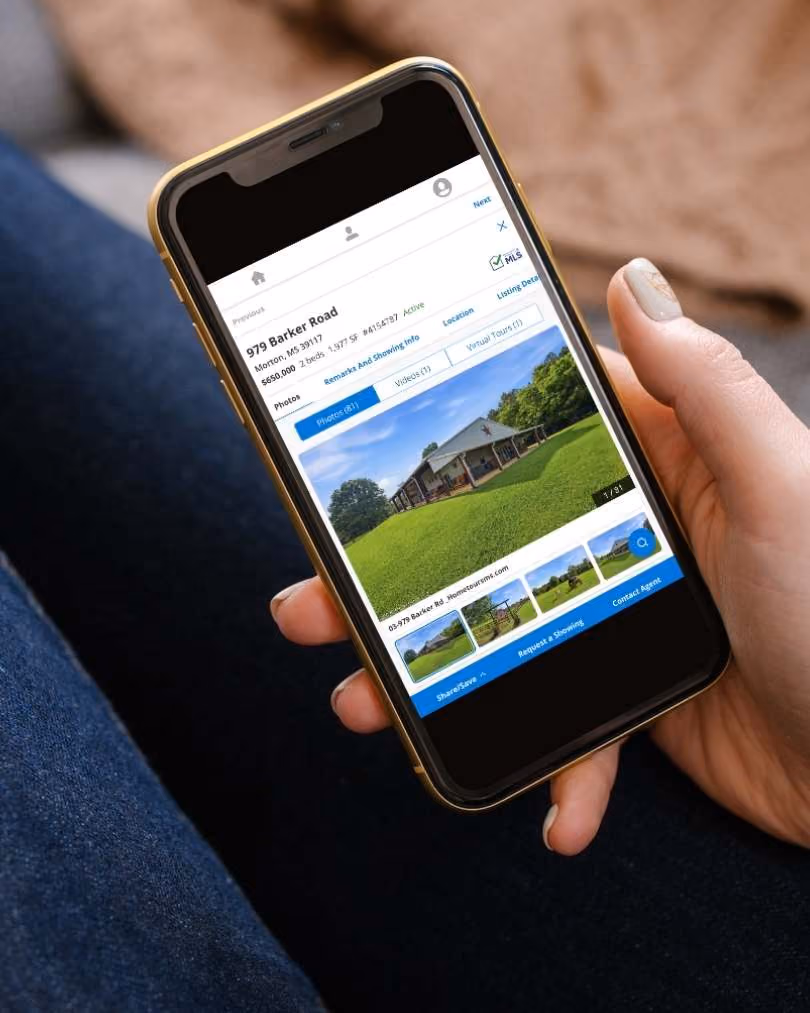 Smartphone showing a Hopper Real Estate Leaders listing for 979 Barker Road in Morton, MS, priced at $650,000 with 2 beds and 3,577 sq ft, highlighting photos of a house with a large green lawn.