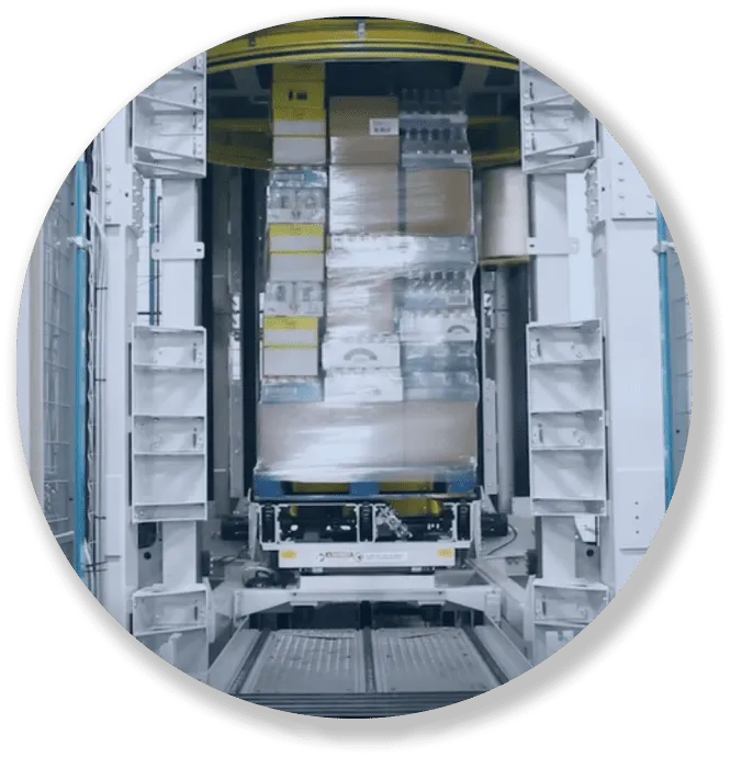 Automated system moving wrapped pallet boxes stacked on a platform inside a warehouse.
