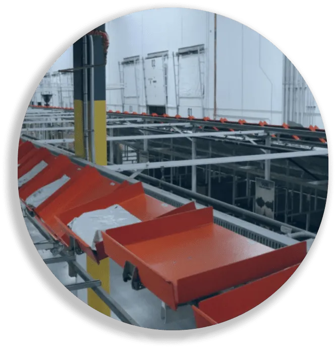 Red conveyor belts in an industrial warehouse with white packages on them.