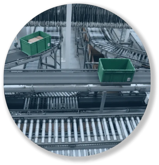 Industrial conveyor system with green plastic bins carrying packages in a warehouse setting.