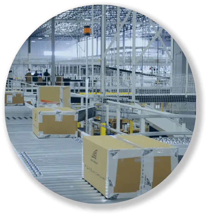 Cardboard boxes on conveyor belts inside a large, modern warehouse or distribution center.