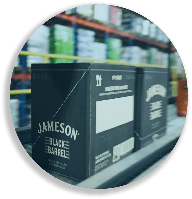 Boxes of Jameson Black Barrel whiskey on a conveyor belt in a warehouse setting.