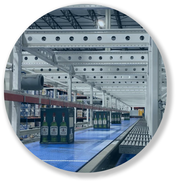 Conveyor belt in warehouse carrying boxes of Jameson whiskey bottles under a metal framework.