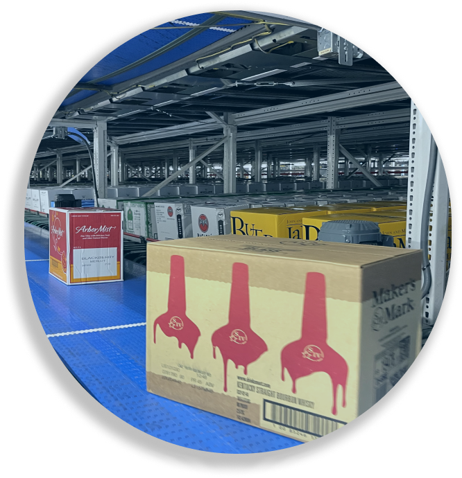 Warehouse conveyor with boxes of Maker's Mark whiskey and Arbor Mist wine on a blue roller conveyor belt.