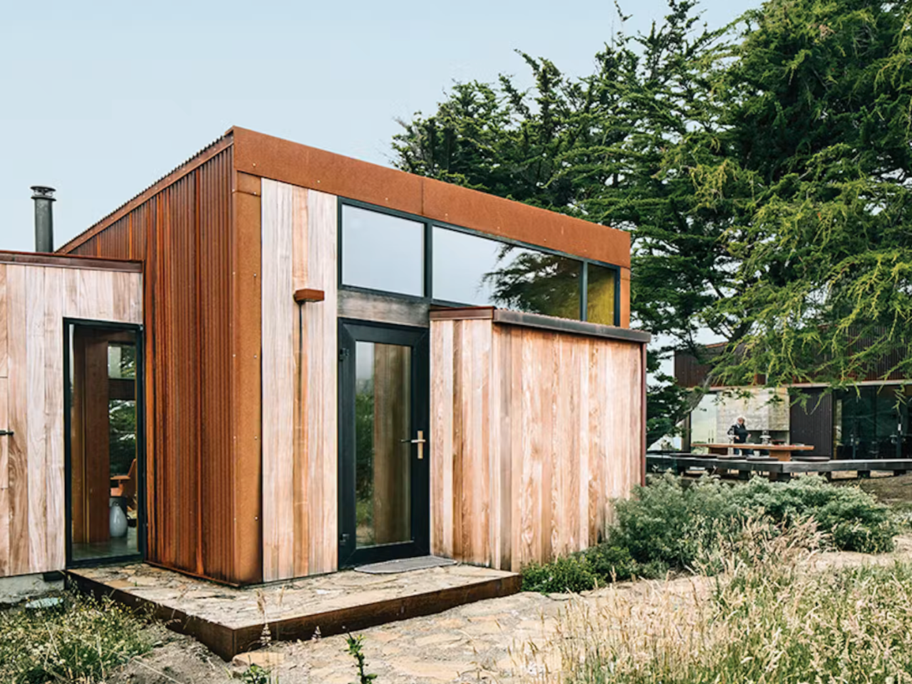 A beautiful home rendering, with large windows, yard, and a car parked in driveway.