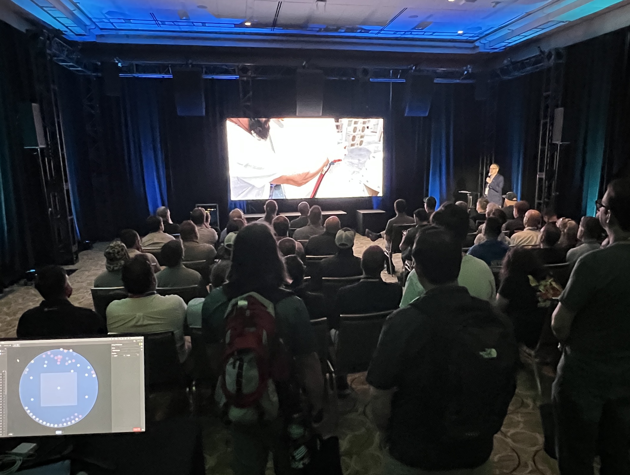 A crowd of people sitting watching a man give a presentation in the front of a room