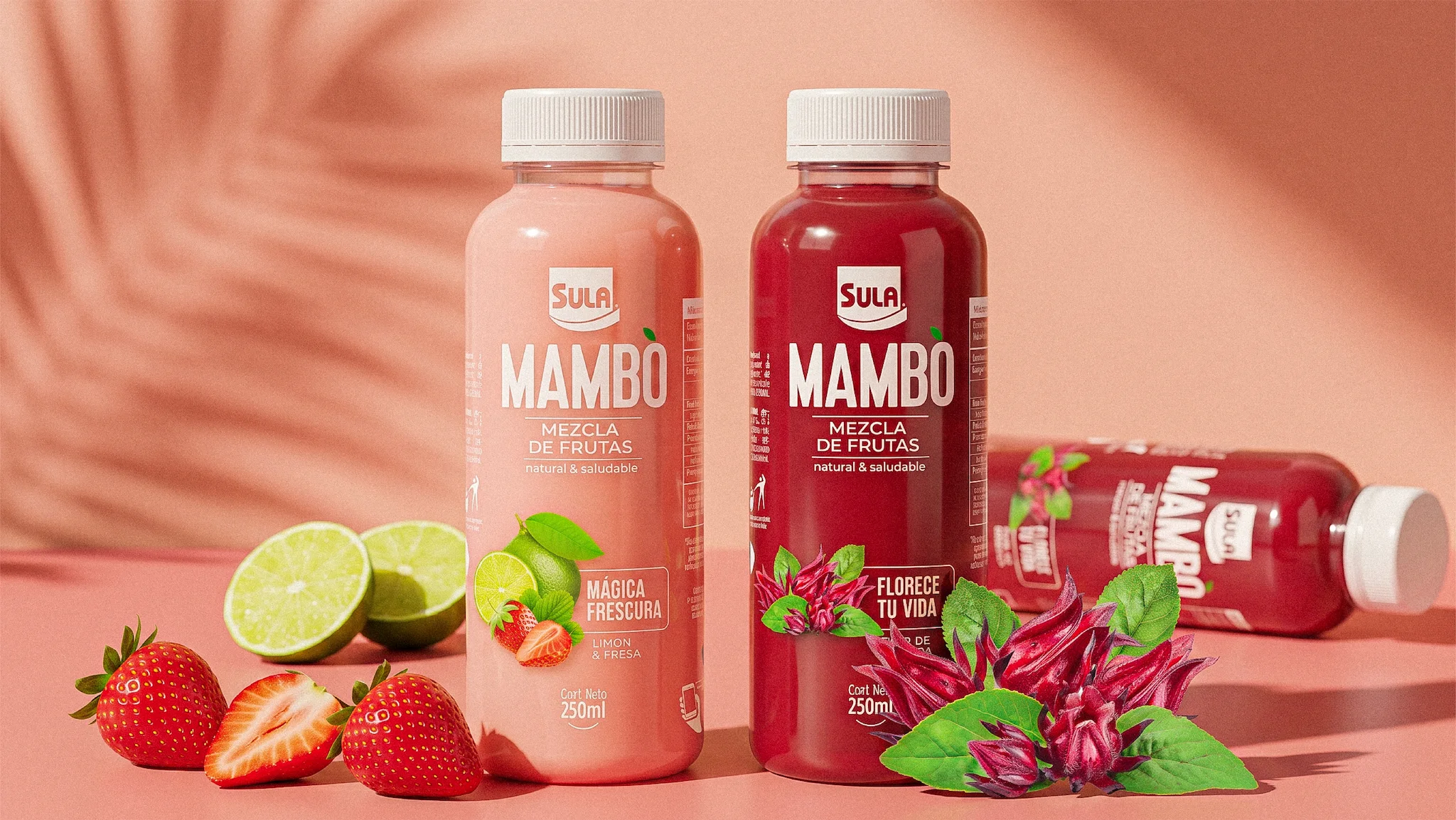 Botellas Mambo Mágica Frescura y Florece Tu Vida rodeadas de fresas, limones y flores de jamaica sobre fondo rosa