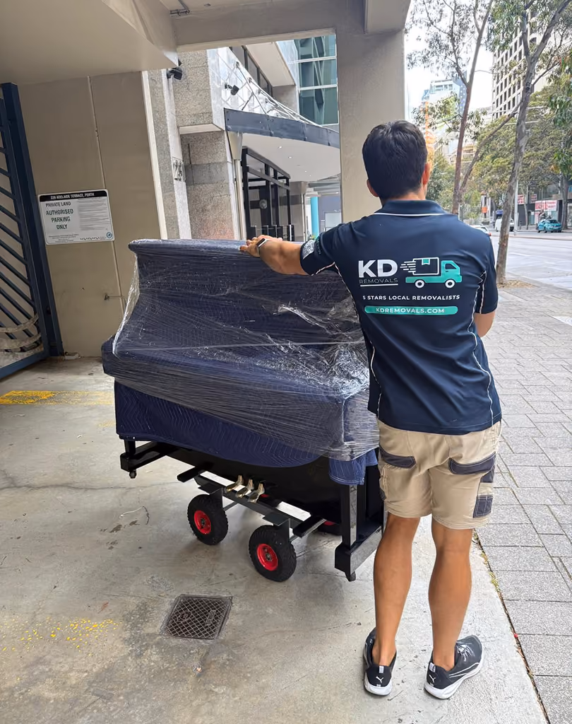 KD removalist moving a piano with protective padding