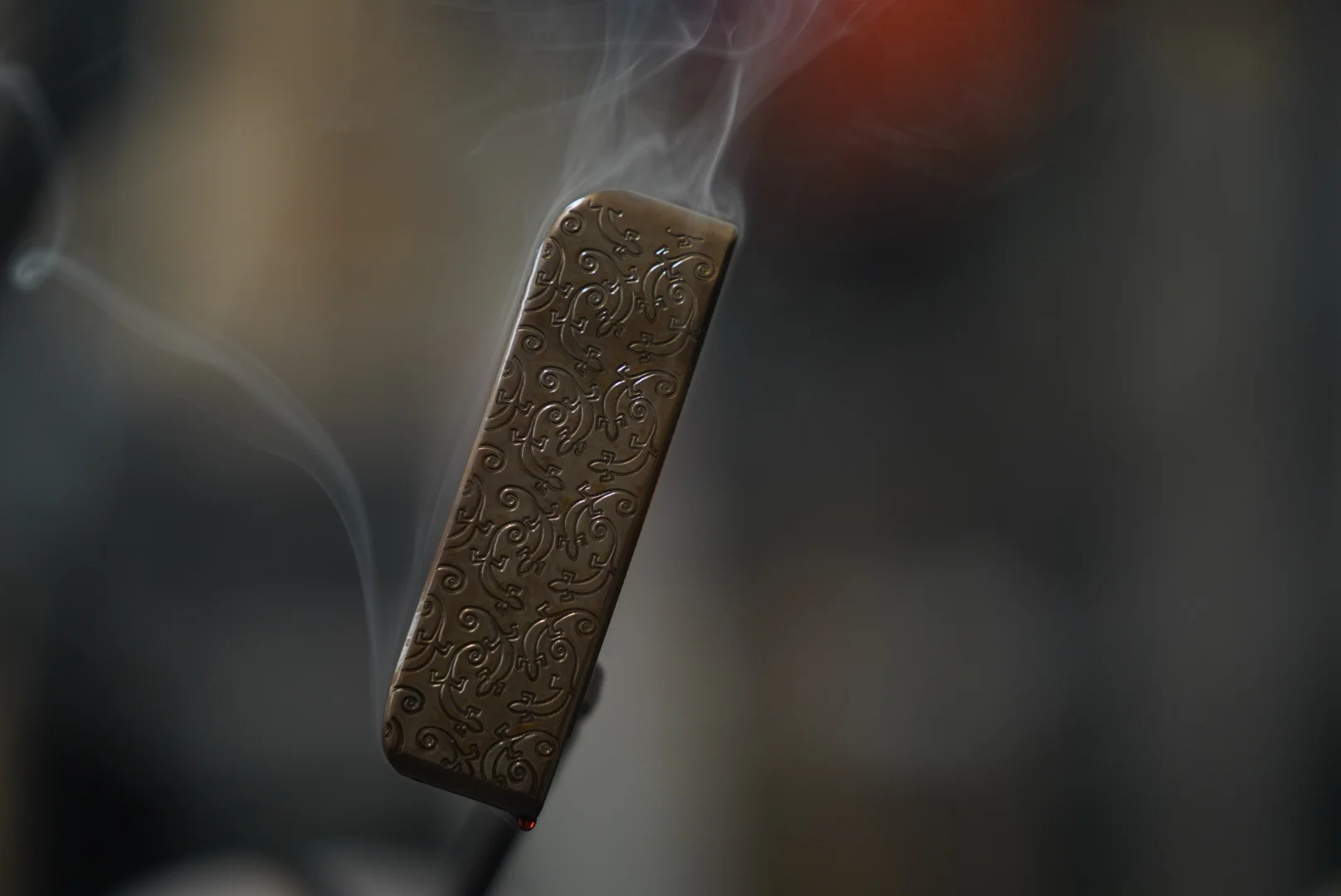 Close-up of an intricately engraved Lajosi putter head during the finishing process, with heat and smoke highlighting the custom detail and hands-on workshop craftsmanship.