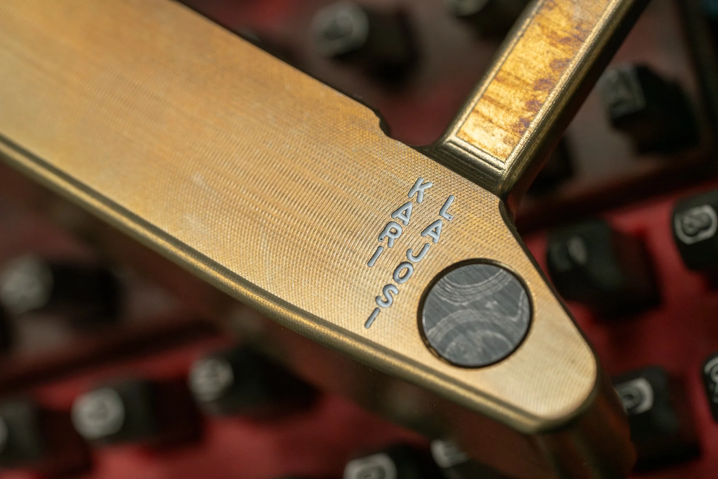 Close-up of a gold-finished Lajosi putter with precision milling, a contrasting circular insert and engraved maker detailing, highlighting the custom craftsmanship behind each club.