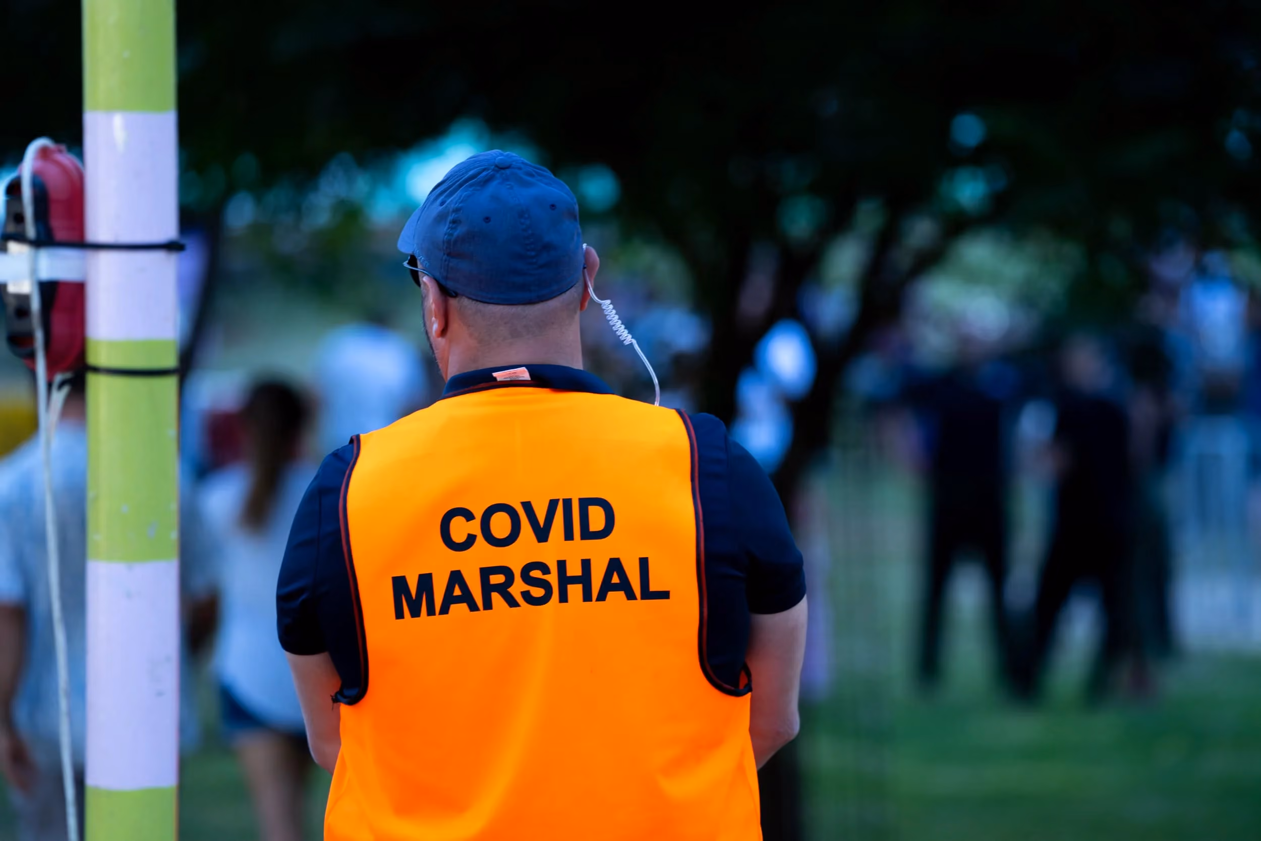 Event safety marshal in a bright orange vest monitoring an outdoor gathering, representing Agile Group’s practical event and safety support services.