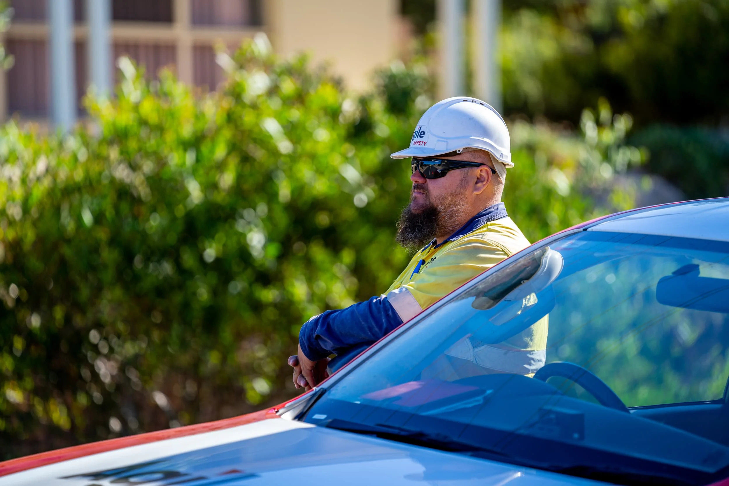 Agile Safety worker in high-visibility gear and a branded hard hat standing beside a fleet vehicle, showing the division’s professional on-site identity within the wider Agile Group brand.
