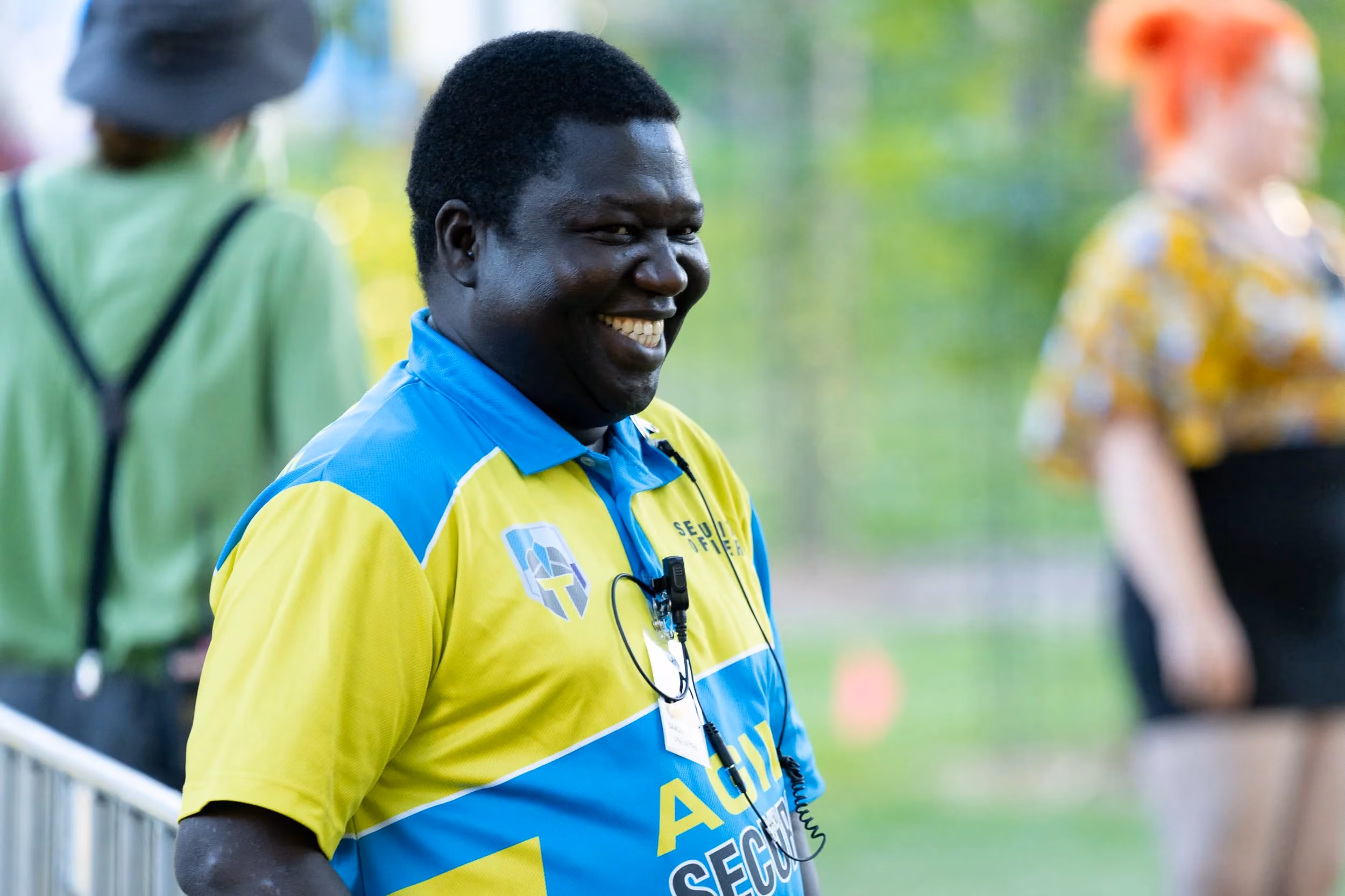 Smiling Agile Security team member in branded high-visibility uniform at an event, showing the division’s clear service identity within the wider Agile Group brand.