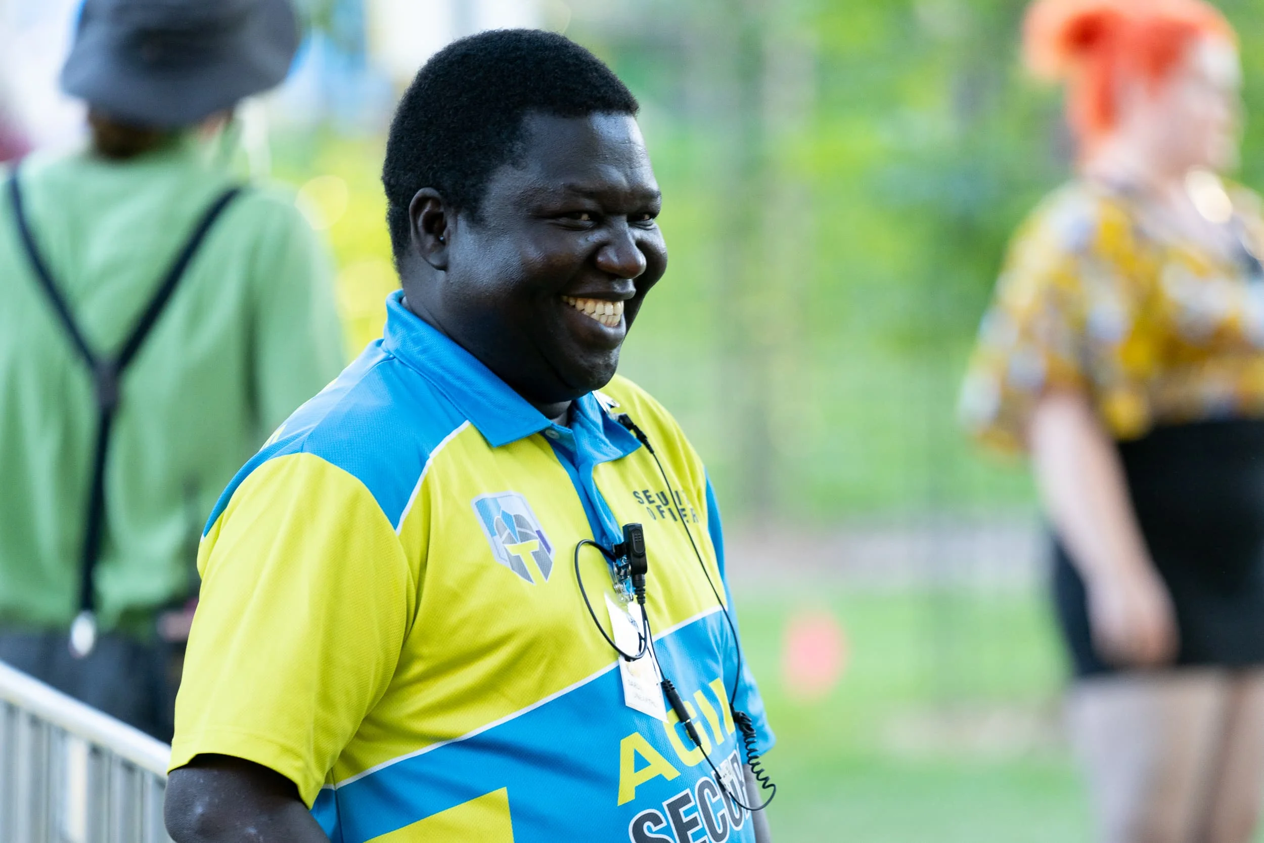 Smiling Agile Security team member in branded high-visibility uniform at an event, showing the division’s clear service identity within the wider Agile Group brand.