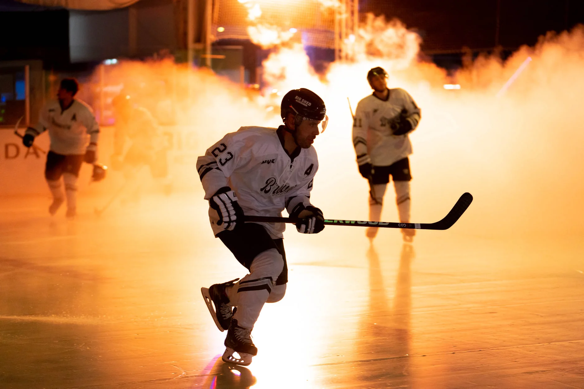 NHSL hockey players skate onto the ice through smoke and bright orange arena lighting, capturing the high-energy game-day presentation that helped the new league feel credible, exciting and worth attending.