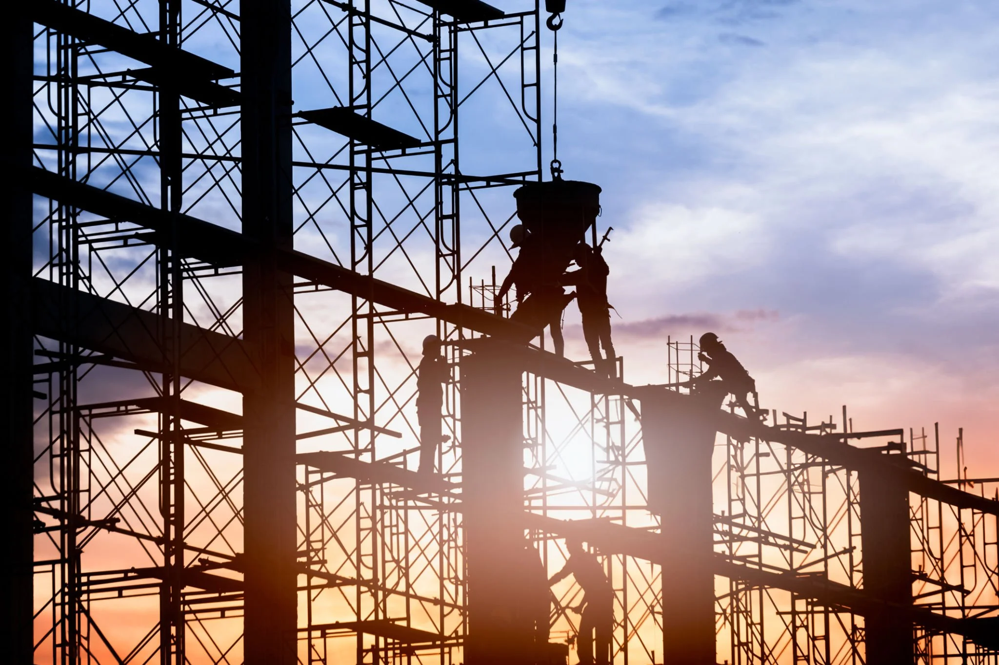 Scaffolding crew working at height on a large commercial construction site at sunset, reflecting MSCaffold’s safety-focused capability for complex access projects.